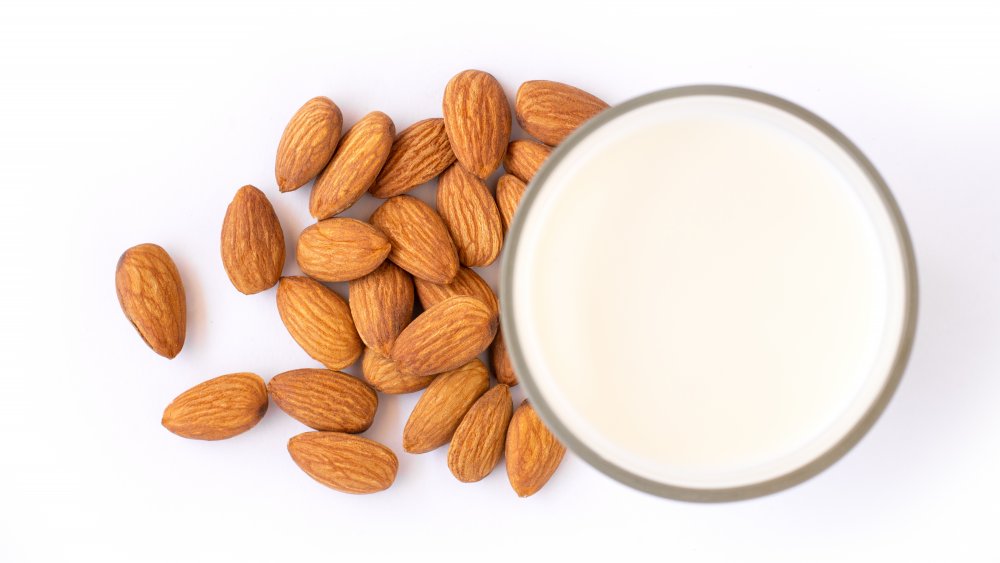 a cup of almond milk next to almonds