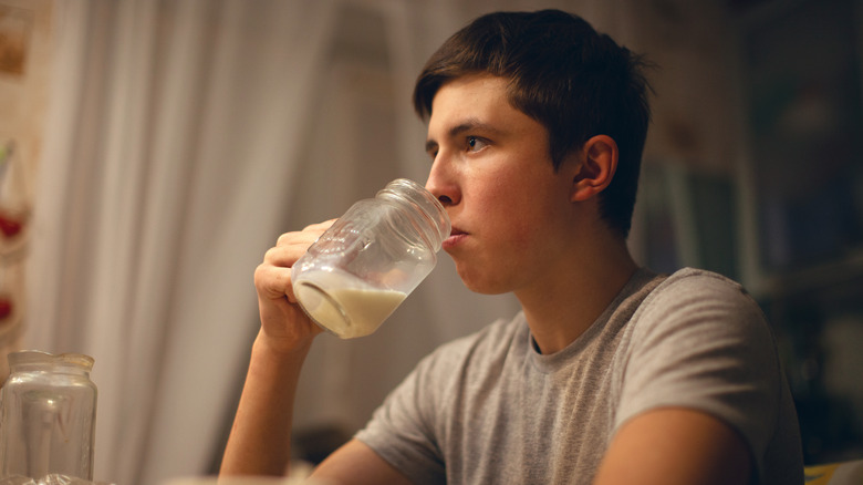 male teen drinking milk in the kitchen 