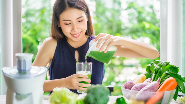 Young woman pouring green juice