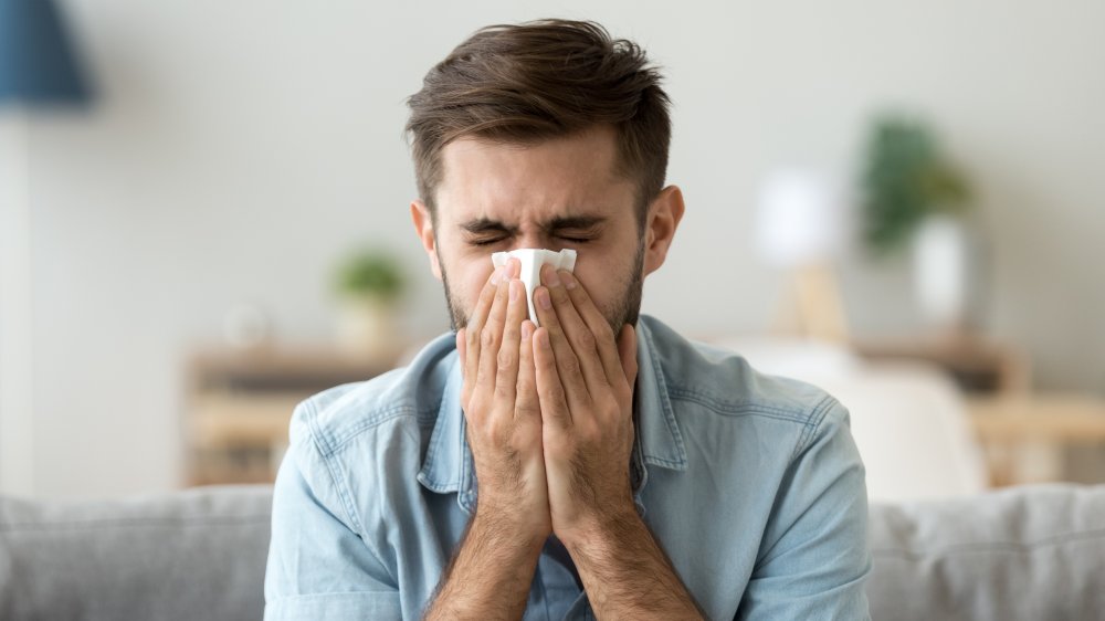 Man sneezes into tissue